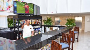 A bar area with a TV displaying a sports event, shelves with bottles, and a counter with a barista.