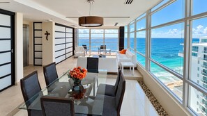 Glass dining table and adjoining living area with panoramic views in this Cancun vacation rental.