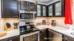 A modern kitchen with dark cabinetry, stainless steel appliances, and a red curtain.