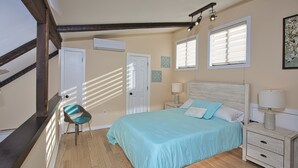 A bedroom with a bed, nightstands, a chair, and a window.