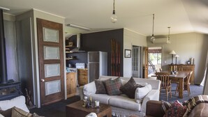 A cozy living room with a fireplace, a dining area with a wooden table and chairs, and a kitchen with a refrigerator and stove.