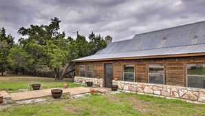 A rustic cabin with a stone foundation, large windows, and a metal roof. - Dripping Springs Home w/ Deck, Near Wedding Venue (Dripping Springs)