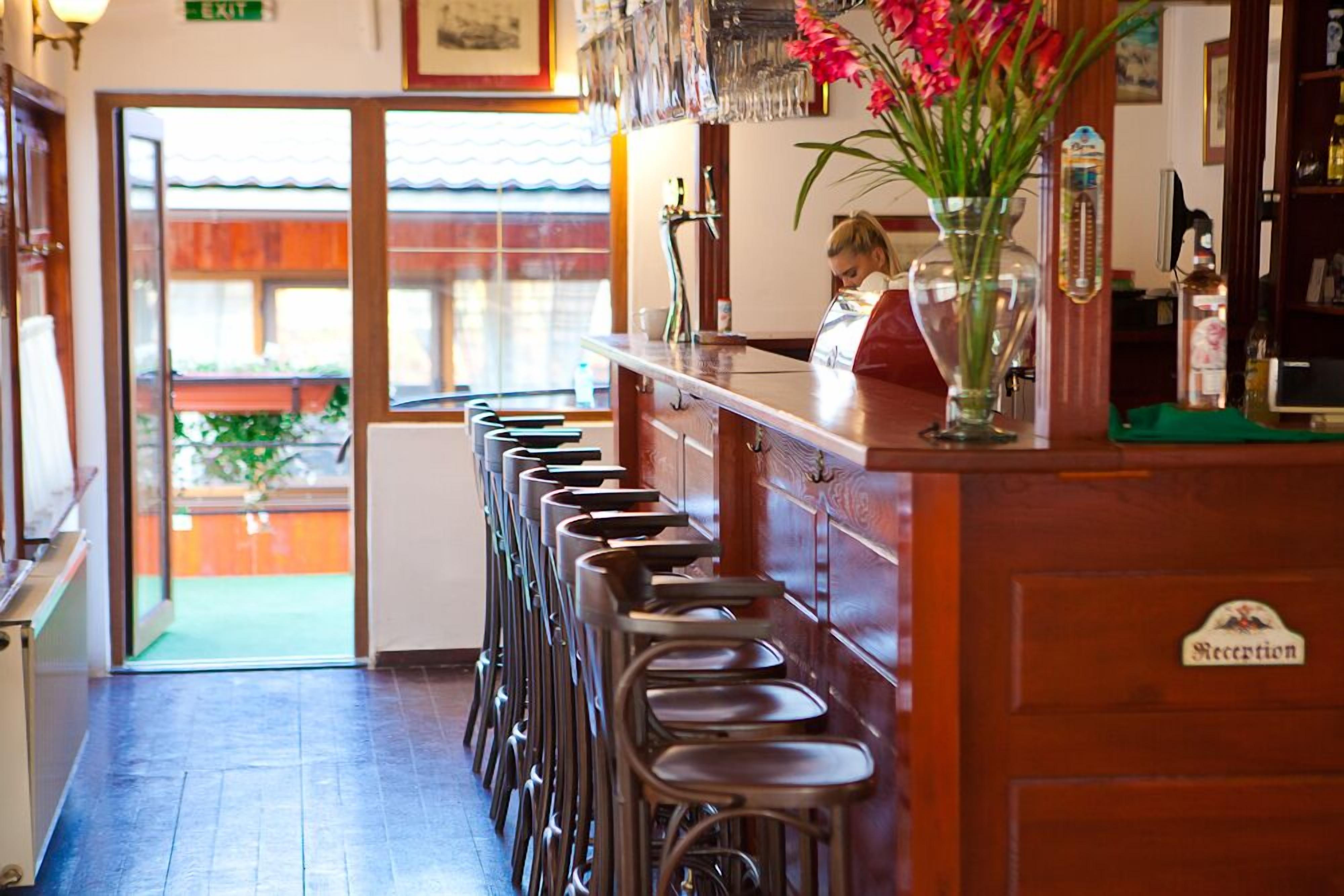 A bar area with stools, a reception desk, and a window with a view of the outside.