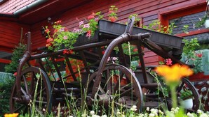 A rustic wooden cart with flower boxes, positioned in front of a red wooden house. - Casa Bazna (Bazna)