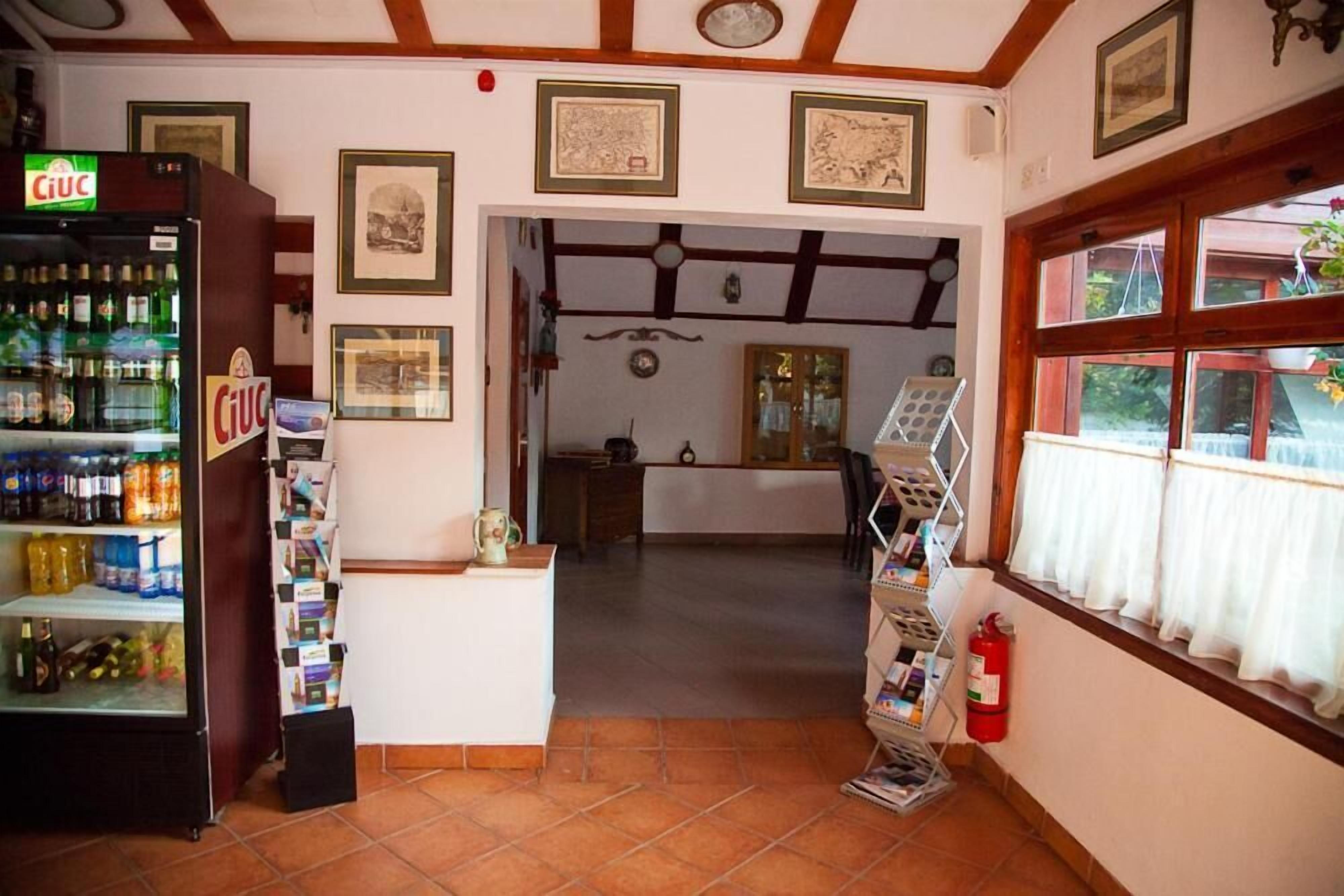 A cozy interior with a tiled floor, a beverage dispenser, framed pictures on the wall, and a window with curtains.