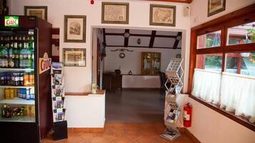 A cozy interior with a tiled floor, a beverage dispenser, framed pictures on the wall, and a window with curtains.