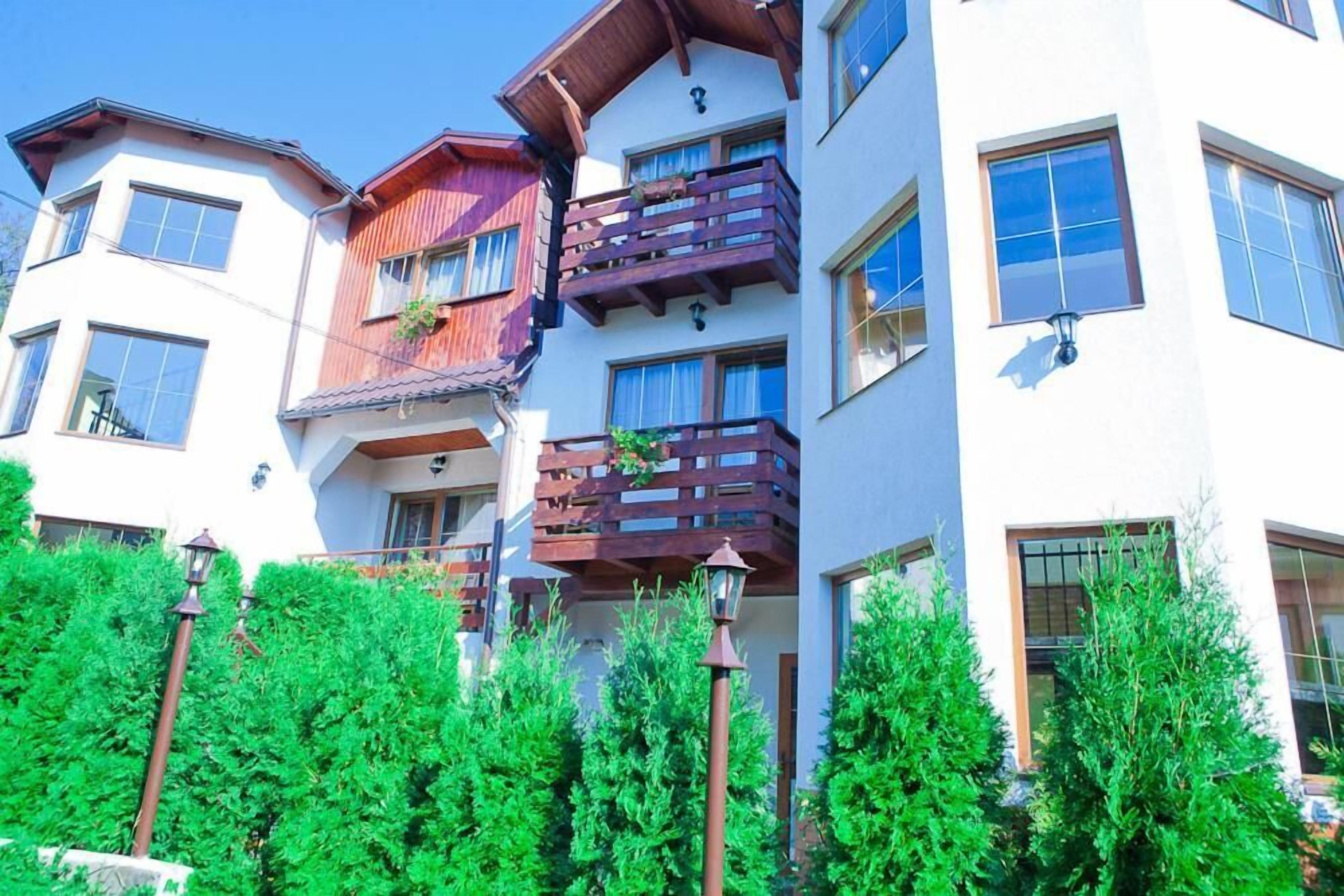 Un edificio de varios pisos con balcones, grandes ventanales y un jardín bien cuidado.