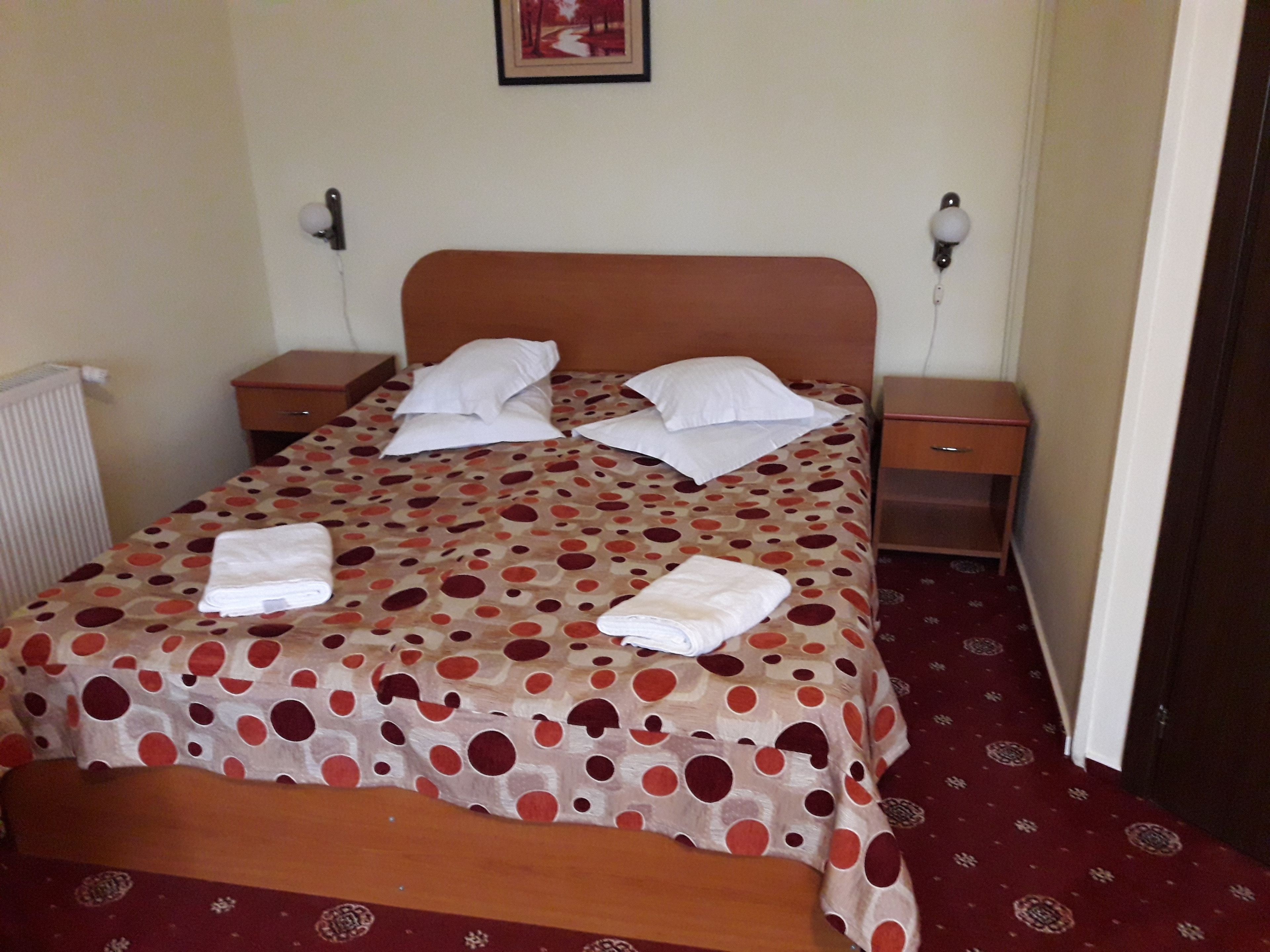 A neatly made bed with a polka dot bedspread, two pillows, and two folded towels on the bed.