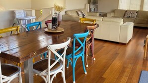 A dining area with a wooden table and chairs, a ceiling fan, and a sofa in the background. - Jan Juc Beach Break - Walk to Beach, Pet Friendly (Jan Juc)