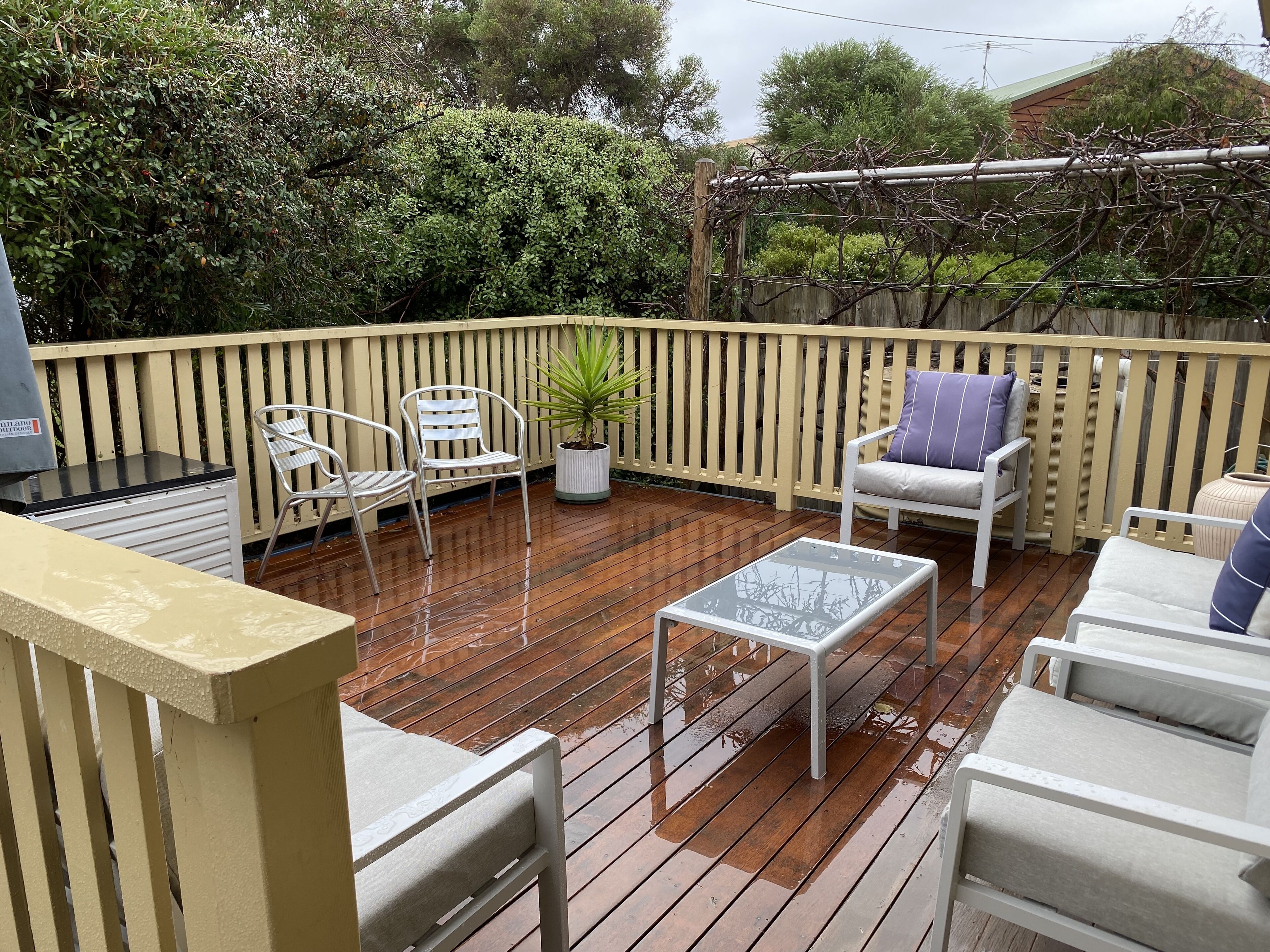 A wooden deck with outdoor furniture, including chairs and a table.