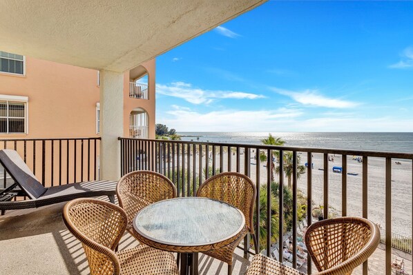 Un balcone con mobili in vimini, un tavolino e vista sulla spiaggia e sull'oceano.