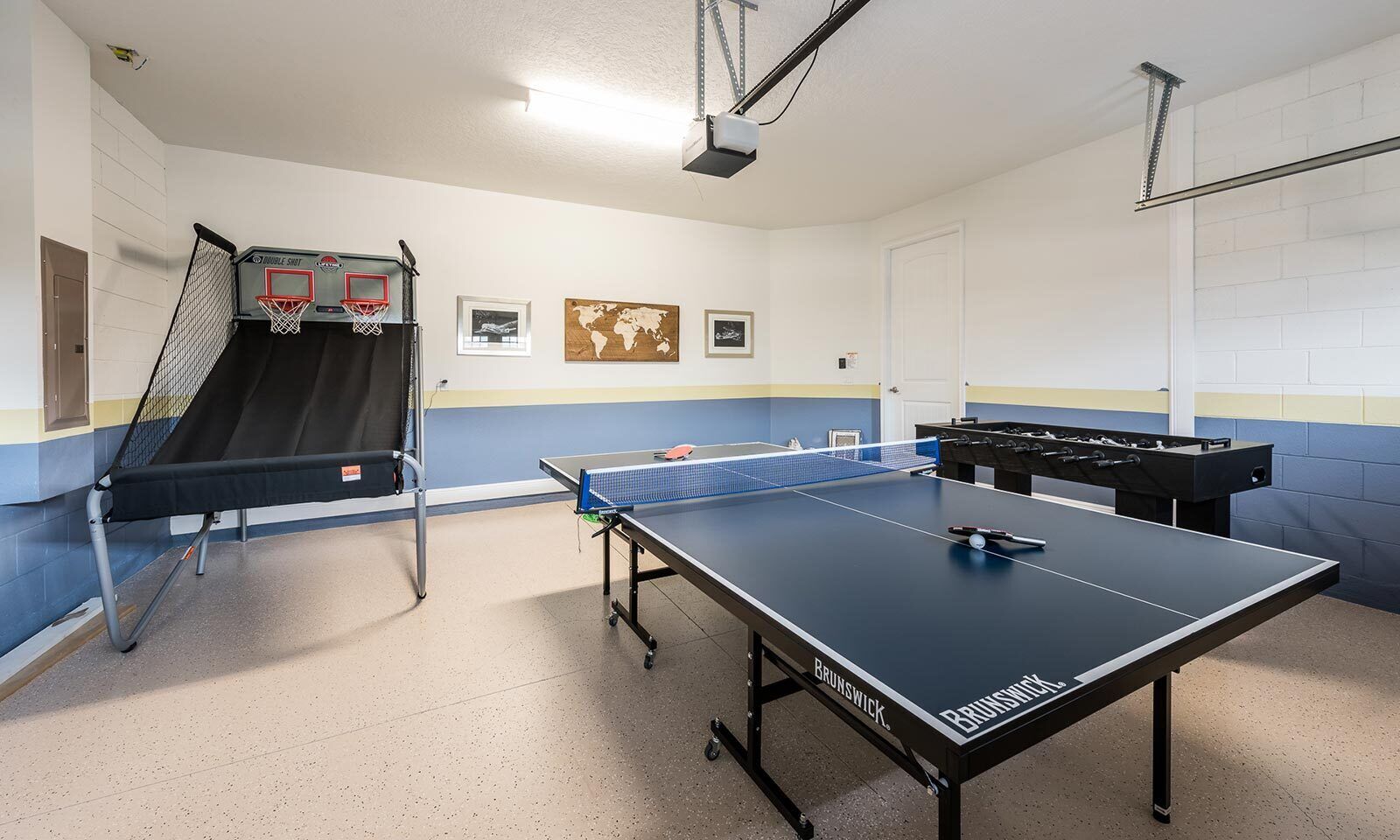 Una sala de recreación con mesa de ping pong, mesa de fútbol de mesa y una cancha de baloncesto en miniatura.