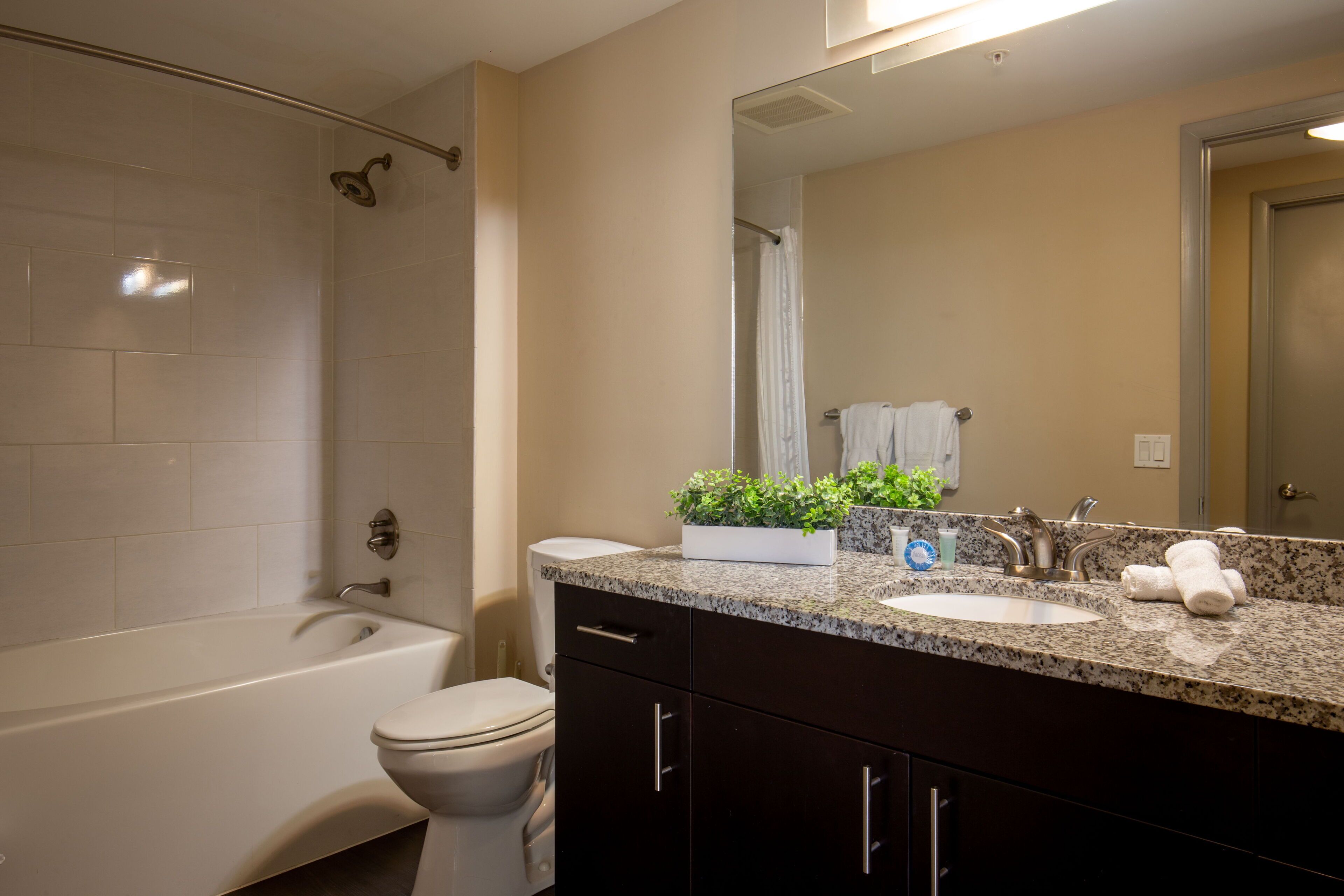 A modern bathroom with a bathtub, toilet, sink, and dark wooden cabinets.
