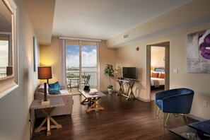 A modern living room with a sofa, a coffee table, a TV, and a blue chair. - Shorecrest Miami Bay (Miami)