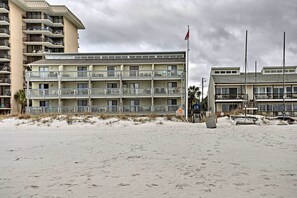 Un hotel fronte spiaggia con diversi balconi, una spiaggia sabbiosa e una bandiera.