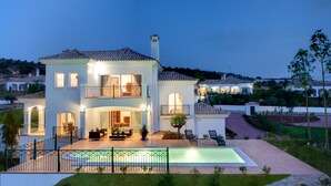 A two-story house with a swimming pool, outdoor seating area, and a well-maintained garden.