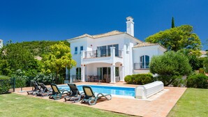 A two-story house with a swimming pool, outdoor seating, and a well-maintained garden.
