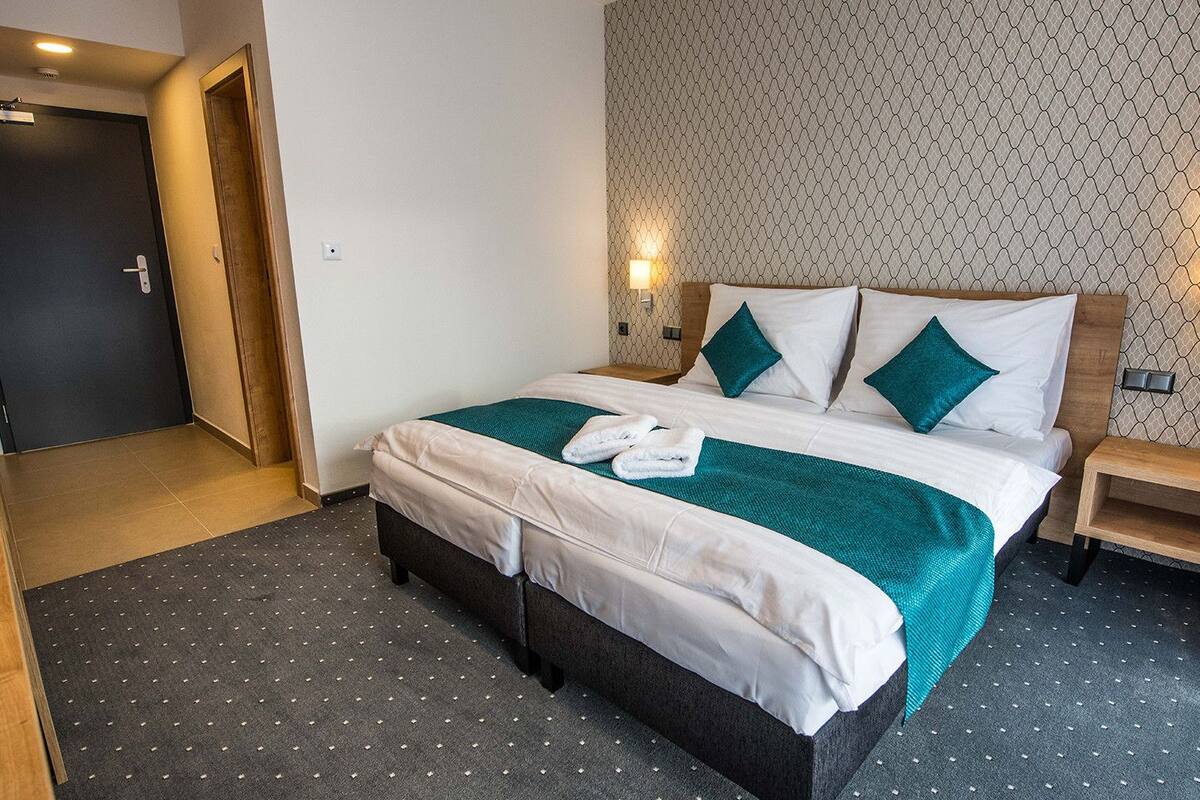 Ett hotellrum med en säng, två sängbord, en dörr och en vägg med ett mönster.