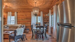 A wooden cabin interior with a dining area, a sofa, and a large refrigerator. - Ruidoso Log Cabin Retreat - Peaceful & Convenient (Ruidoso)