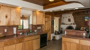 A kitchen with wooden cabinets, a dishwasher, a sink, and a brick fireplace. - Beautiful home with pool, private, close to UA & Downtown, arts. Great prices! (Tucson)