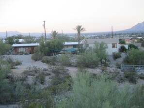 A rural area with sparse vegetation, a few buildings, and a distant mountain range. - Beautiful home with pool, private, close to UA & Downtown, arts. Great prices! (Tucson)