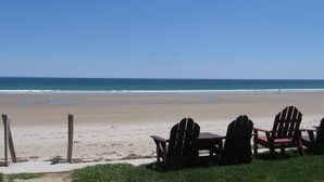 A beach with a wooden table and four Adirondack chairs facing the ocean. - Moody Beach Front Studio Cottage WIFI (Wells)