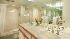Un baño moderno con dos lavamanos, ducha e inodoro.