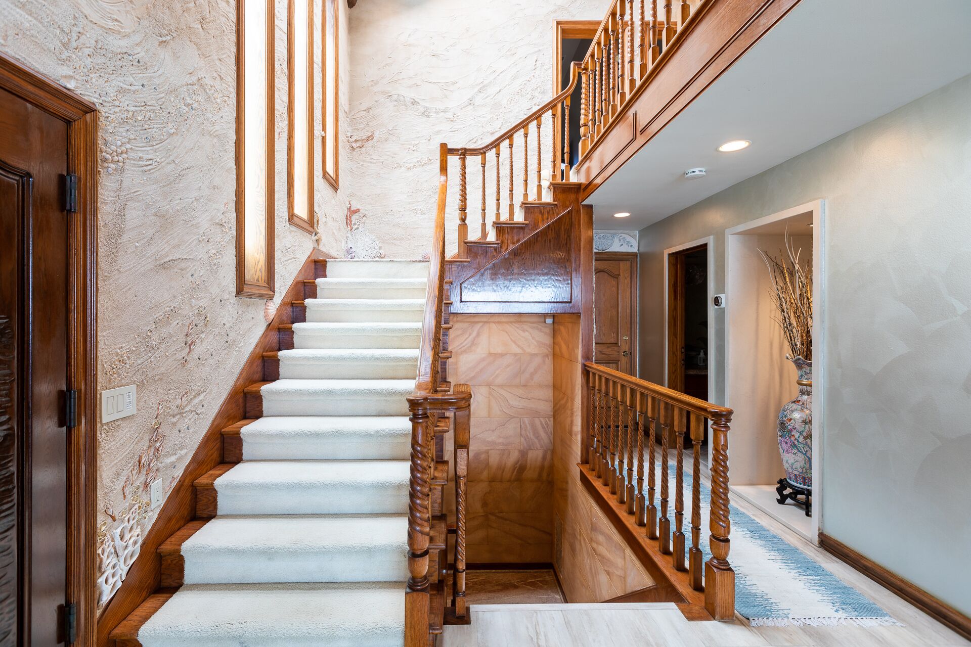A staircase with wooden railings and a marble wall.
