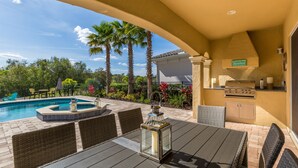 Une terrasse extérieure avec une piscine, des meubles en osier, un barbecue et un panneau indiquant « Pieds nus ».
