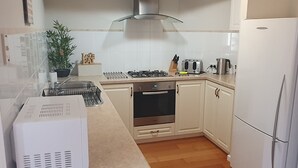 A modern kitchen with white cabinets, a gas stove, a toaster, and a refrigerator. - Palm Beach Manor ... (Rockingham)