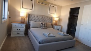 A bedroom with a tufted headboard, two bedside tables, a wardrobe, and a door. - Palm Beach Manor ... (Rockingham)