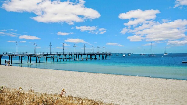 A beach with a pier extending into the sea, clear skies, and calm waters. - Palm Beach Manor ... (Rockingham)