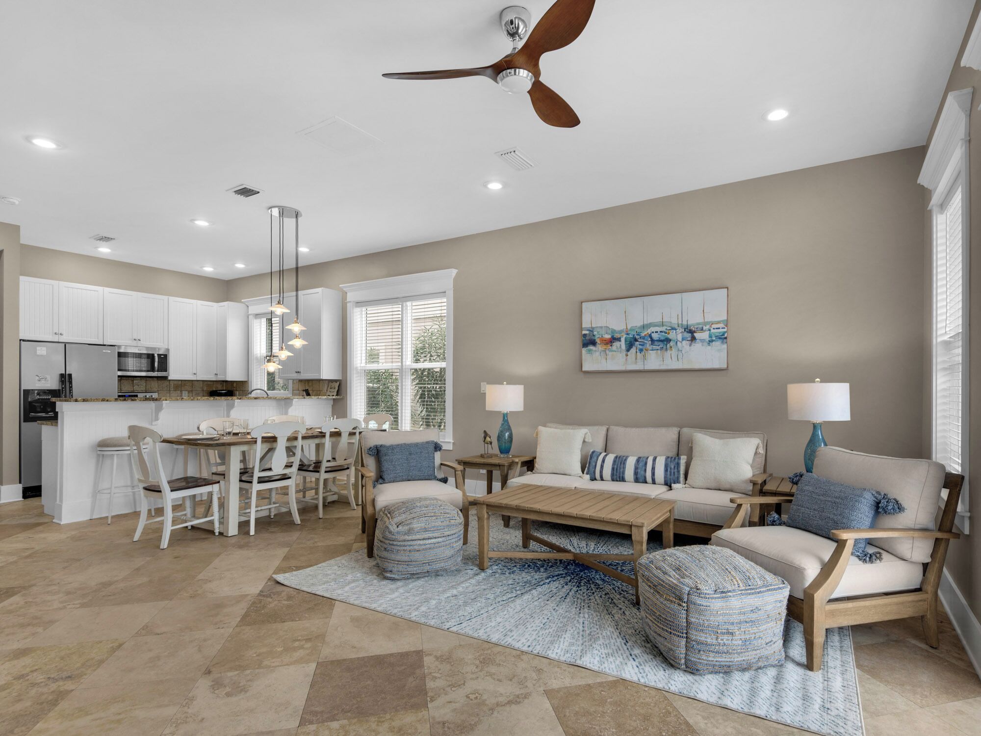 A spacious living area with a dining table, sofas, and a ceiling fan.