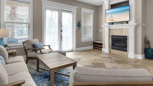 A living room with a fireplace, a television mounted above it, and a ceiling fan. - Spacious Rental, Three Story Townhome, Close to Pool (Miramar Beach)