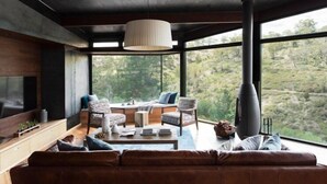 A modern living room with a large window, a fireplace, and a sofa.