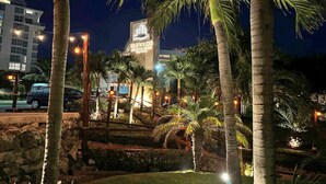 A nighttime view of a hotel with a prominent sign, palm trees, and street lights. - Enjoy Huge Private Terrace with Hot Tub - Beachfront! (CANCUN)