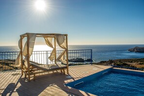 A wooden deck with a pool, a wooden chair, and a canopy overlooking the sea. -  Villa Irene traditional with private pool offering privacy and amazing views! (Livadia, Chania)