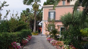 Uma rua de pedras que leva a um edifício com fachada rosa e uma varanda.