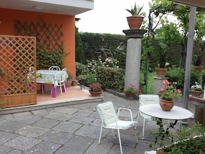 An outdoor patio with a table and chairs, surrounded by potted plants and a wooden fence. - Villa Raffaela - House, ideal for a holiday pacevole (Ercolano)