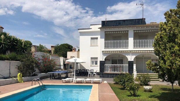 Un bâtiment à deux étages doté d’une piscine, de mobilier d’extérieur et d’un jardin.