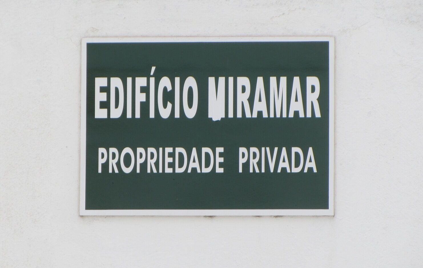 Une pancarte indiquant « EDIFÍCIO MIRAMAR, PROPRIÉTÉ PRIVÉE » est affichée sur un mur blanc.
