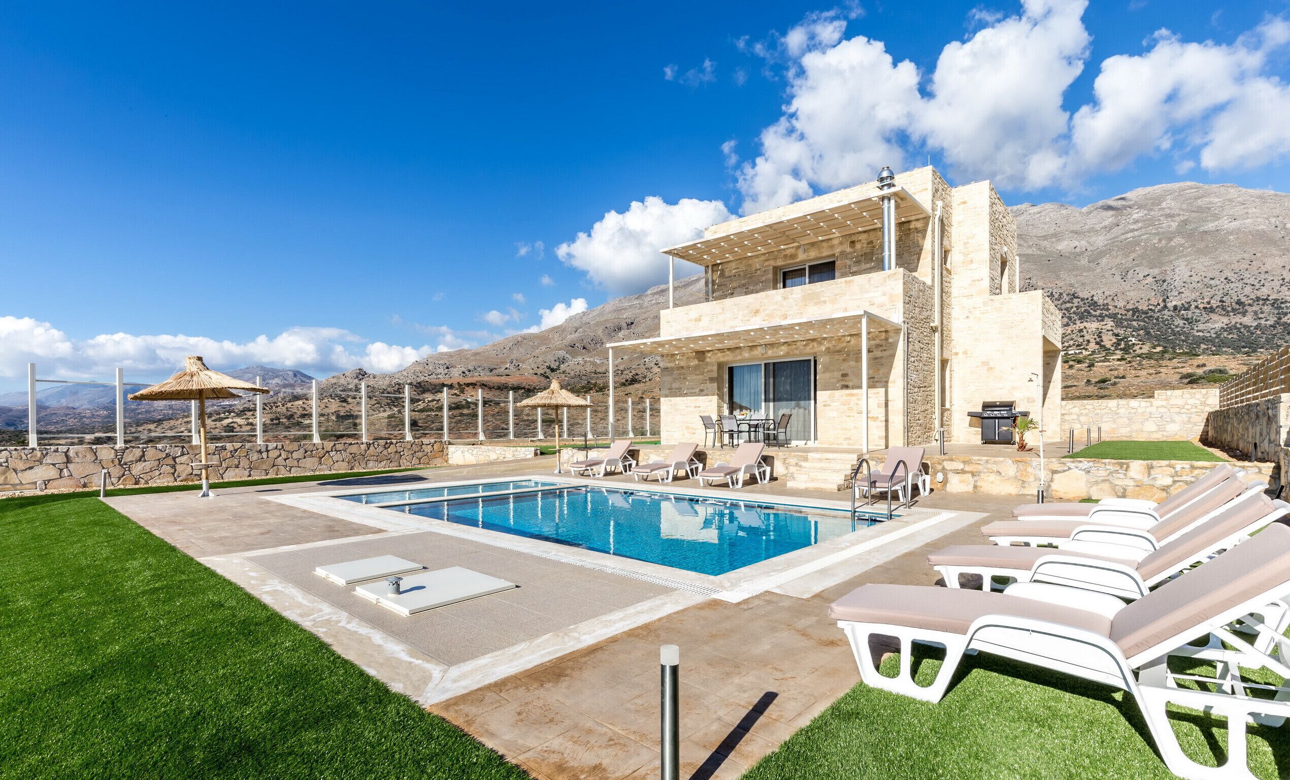 Eine moderne Villa mit Pool, Sitzgelegenheiten im Freien und Bergblick.