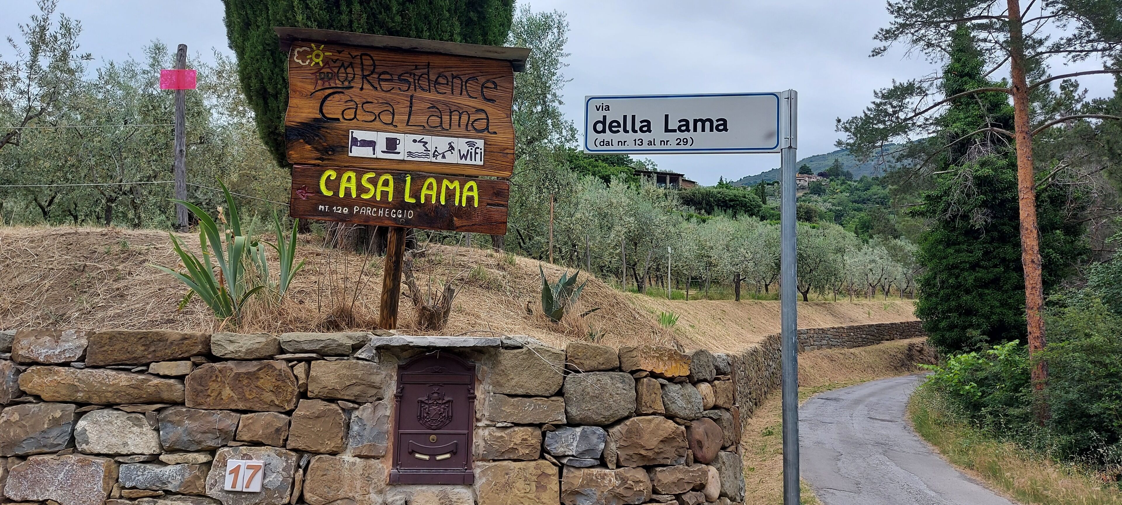 Une enseigne en bois, adossée à un mur de pierres, indique l’emplacement de Casa Lama.