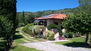 A house with a red-tiled roof, surrounded by lush greenery and a well-maintained garden.
