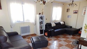 A living room with a sofa, ottoman, and a black leather couch. There is a radiator, a bookshelf, and a chandelier. - Town House With Private Pool ,Good WiFi. Short walk to Villamartin Plaza (alicante)