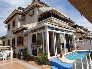 A multi-story house with a swimming pool, large windows, and outdoor seating.