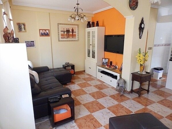 Uma sala de estar com sofá, TV e um armário.