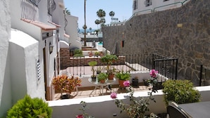A courtyard with a pool, potted plants, and a stone wall. - "🏖 Double terrace with sun all day - 2 bedrooms - Perfect for 4 - Mogán (Mogán)