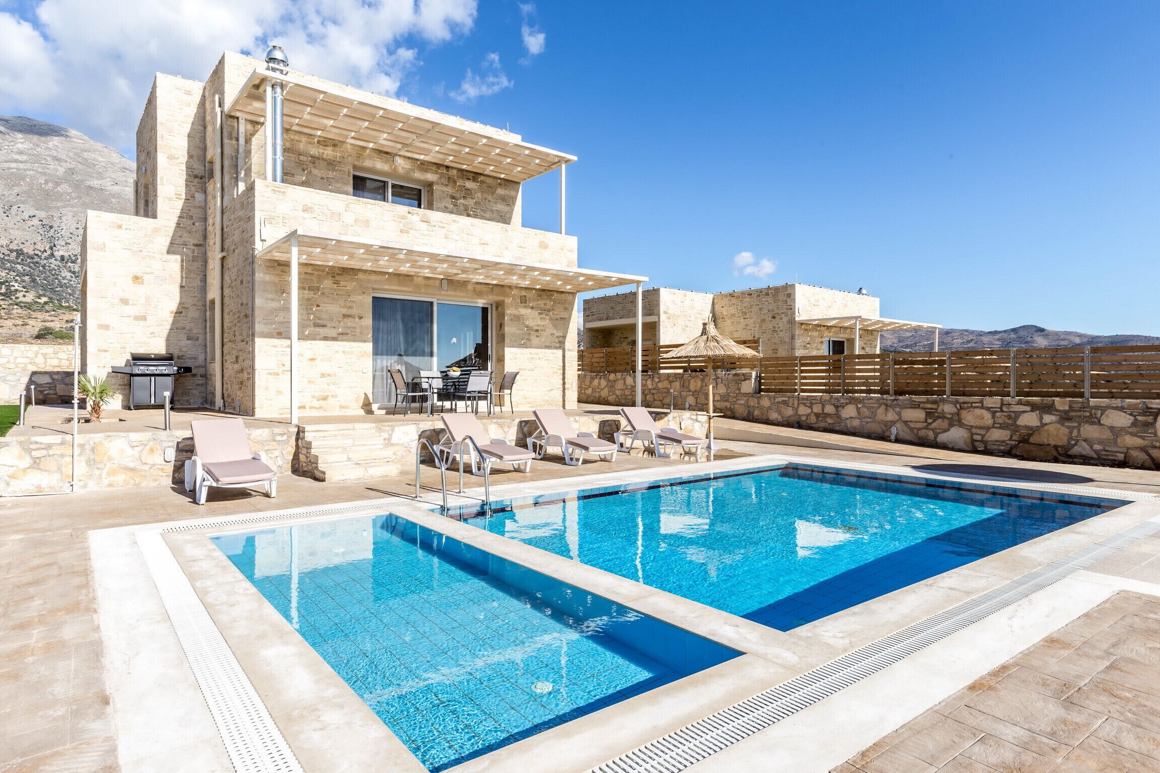 Ein modernes Haus mit Swimmingpool, Steinmauern und Sitzgelegenheiten im Freien.