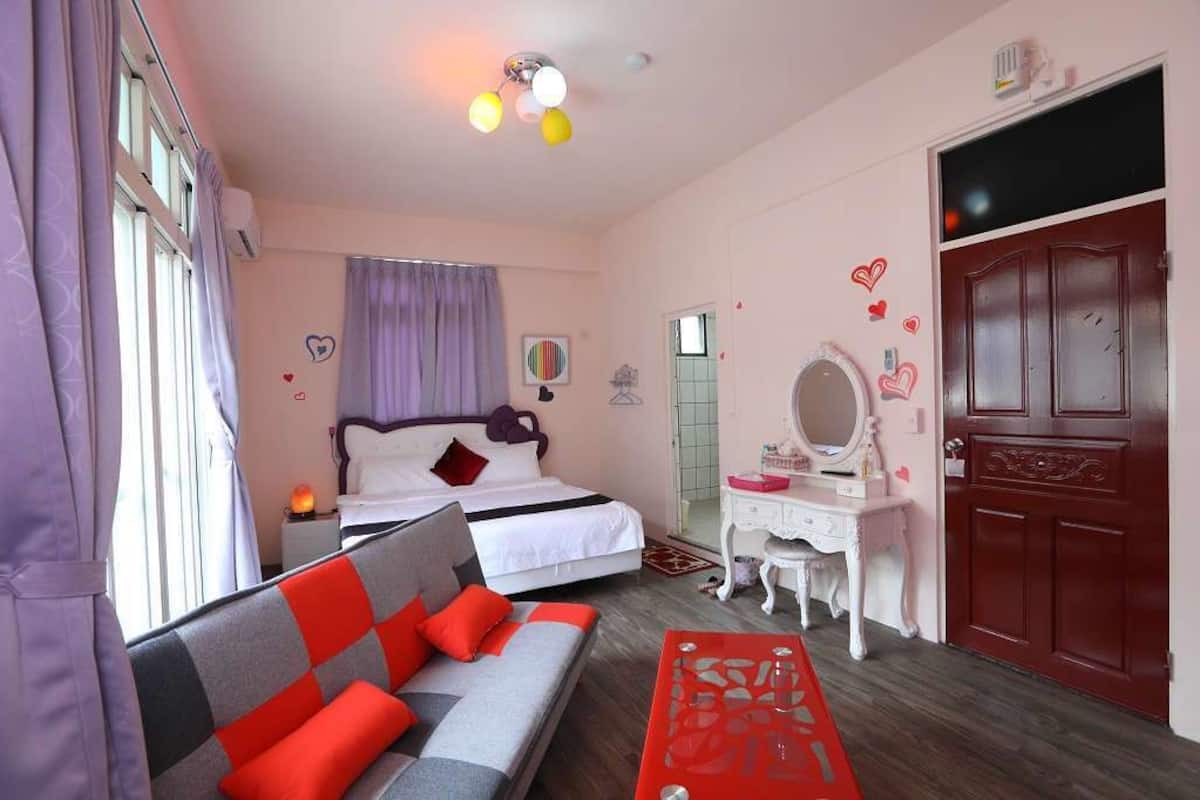 A bedroom with a bed, a sofa, a dresser, and a door.